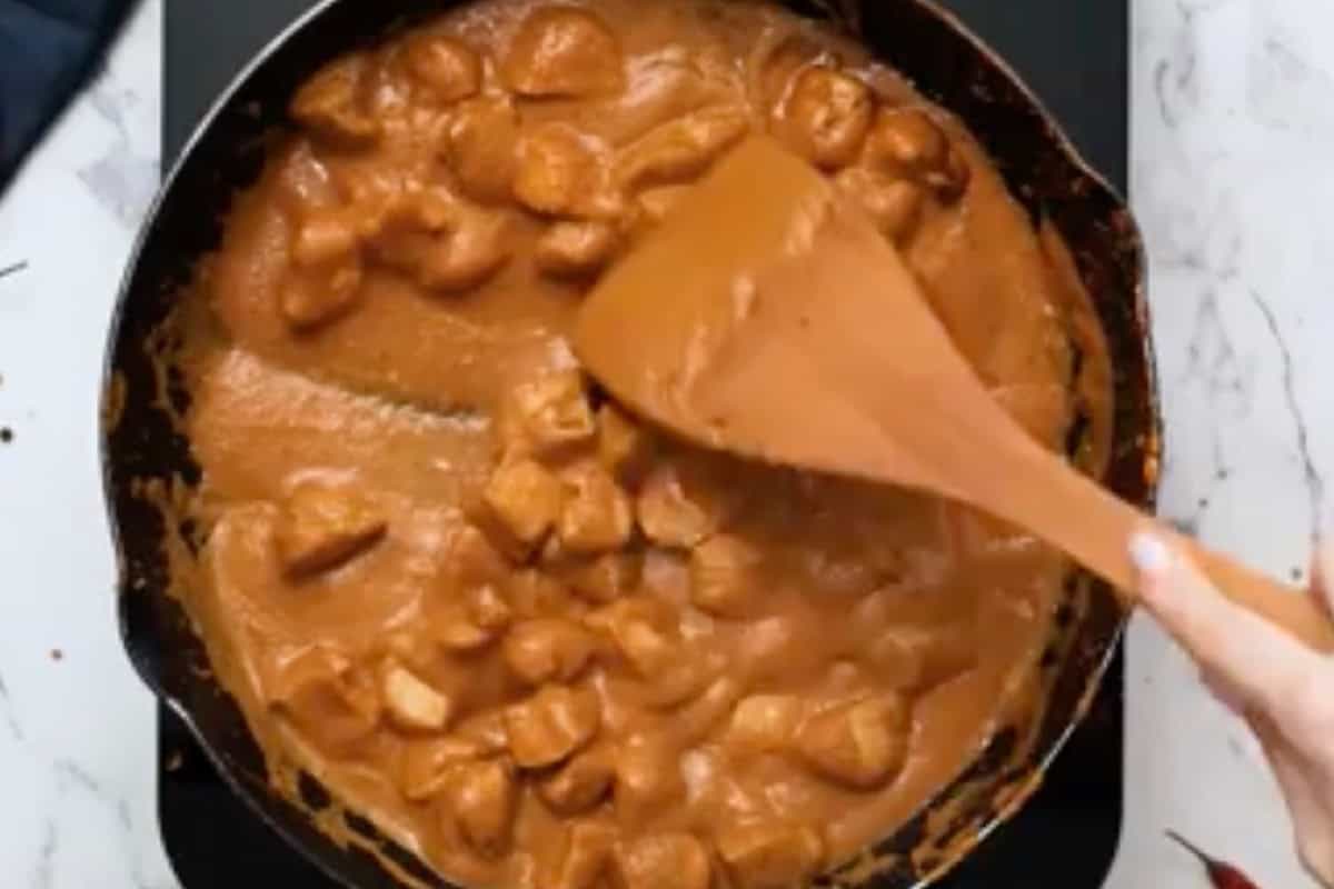 creamy butter chicken in a skillet with a wooden spatula.