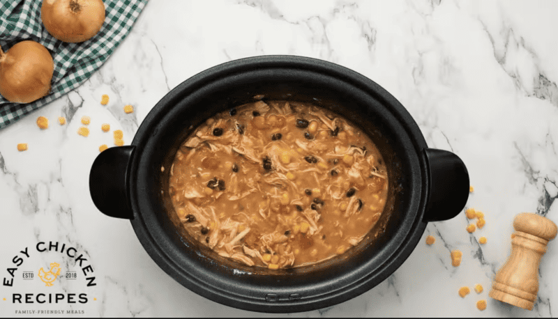 Chicken Enchilada Soup cooked in a crock pot on a marble table.