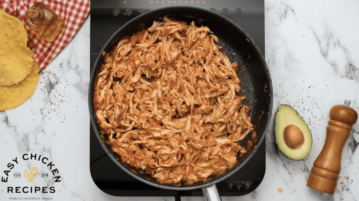 Chicken tinga is fully cooked in a skillet. 