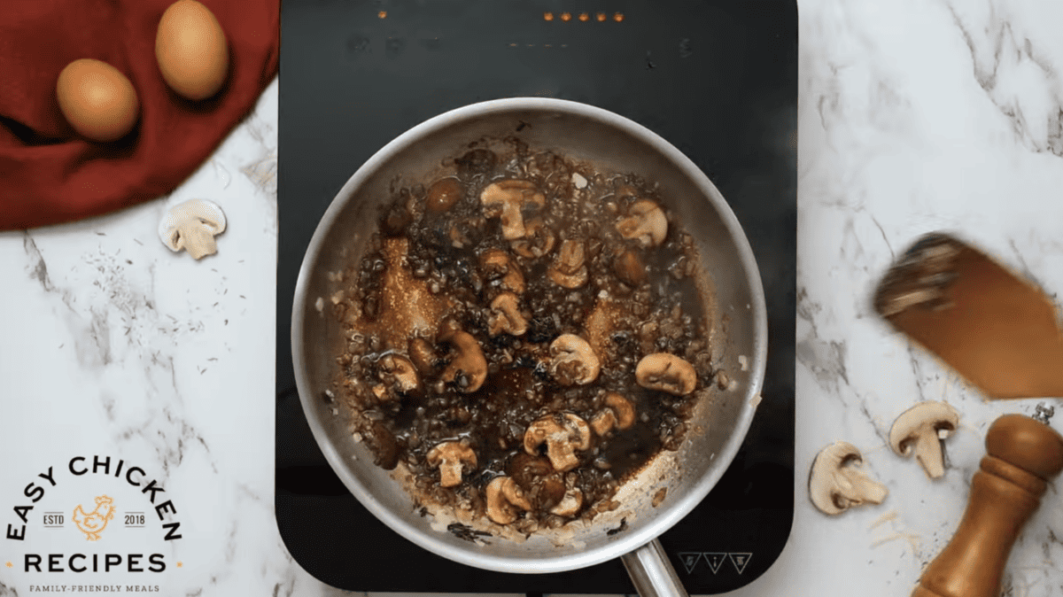 Onions, mushrooms, herbs, garlic and soy sauce are cooking in a skillet. 