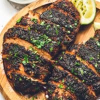 up close image of blackened chicken on wooden plate