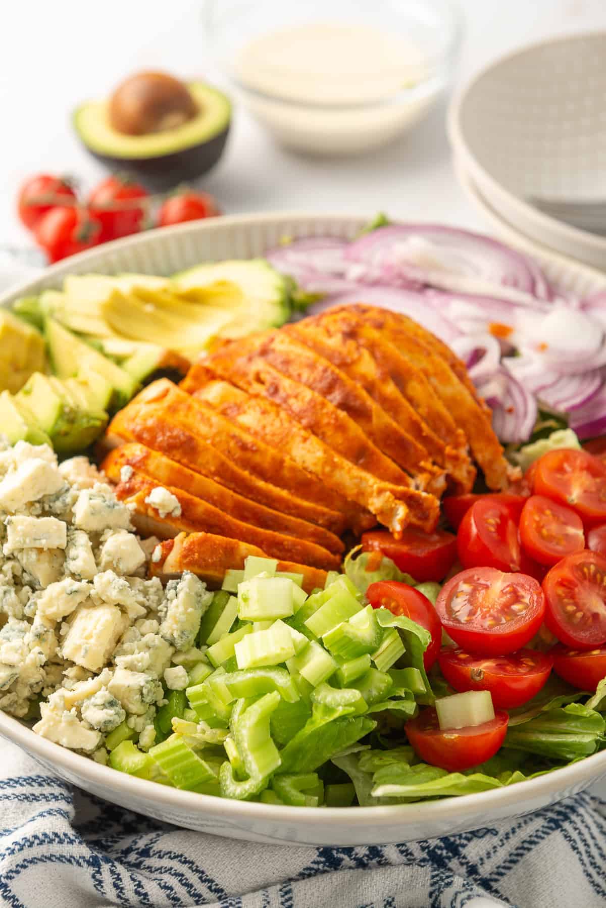 a bowl of buffalo chicken salad with tomatoes, lettuce and blue cheese.