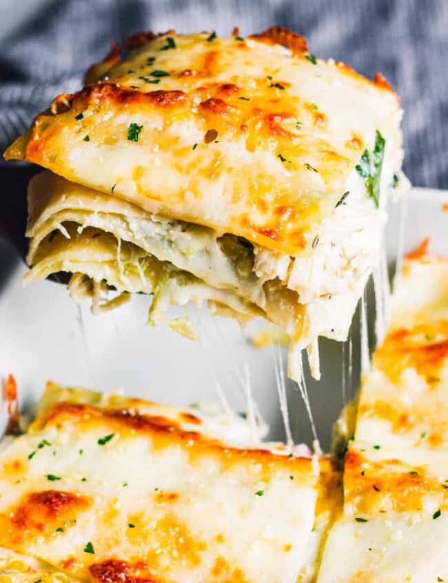 lifting up slice of white chicken lasagna