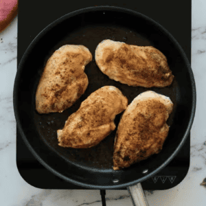 Chicken breasts are seared in a skillet.