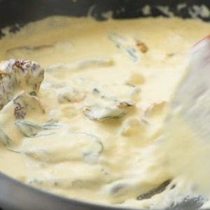A creamy sauce is cooking in a skillet.
