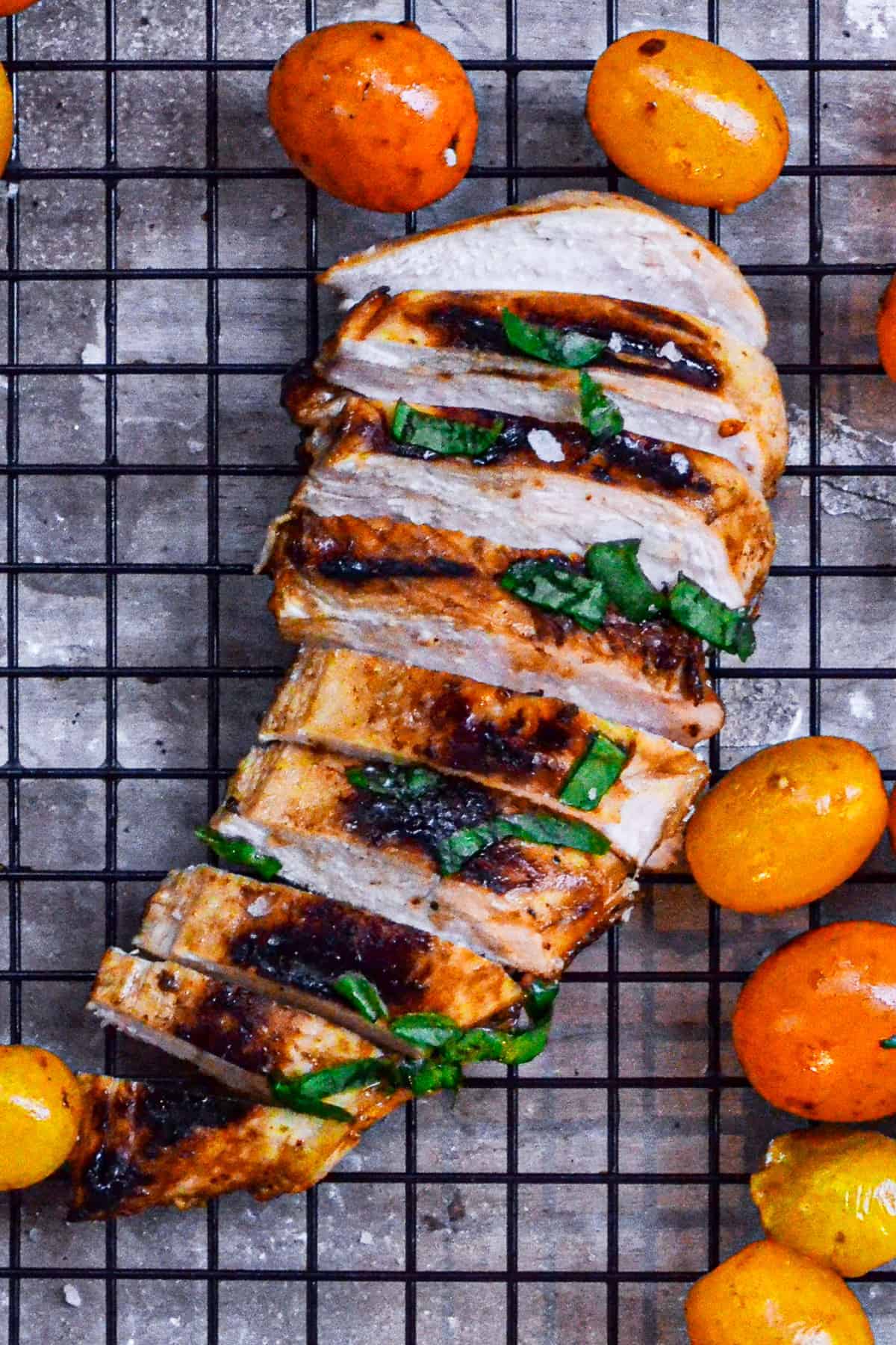 Grilled balsamic chicken with tomatoes and herbs on a cooling rack.