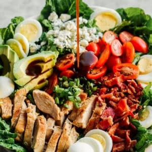 pouring dressing on chicken cobb salad