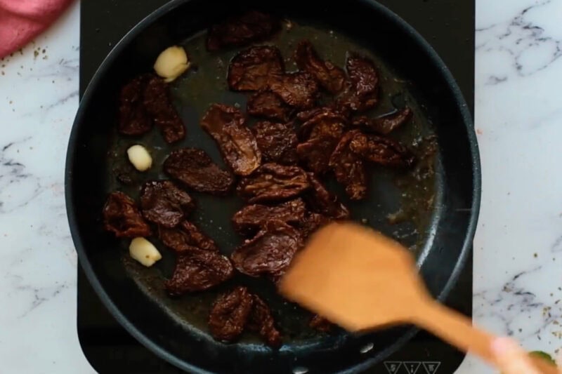 sauteeing sun-dried tomatoes and garlic in a skillet.