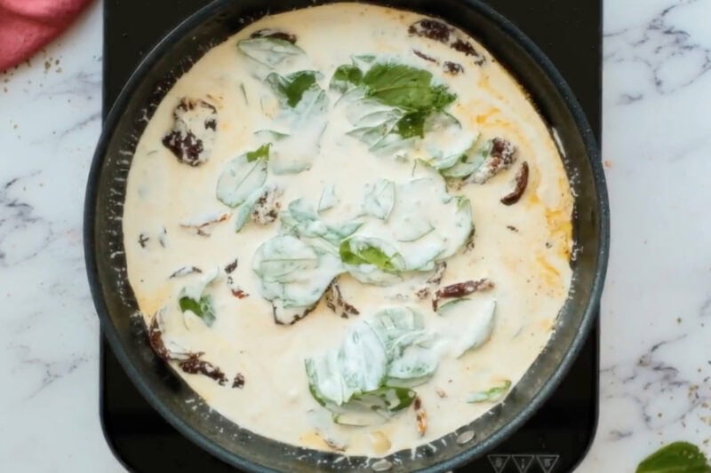 cream and spinach added to sun-dried tomatoes and garlic in a skillet.