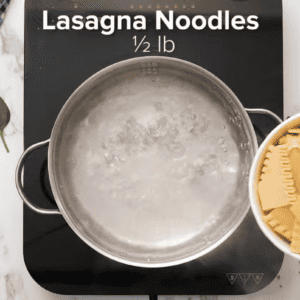 Lasagna noodles are being placed into a pot of boiling water.