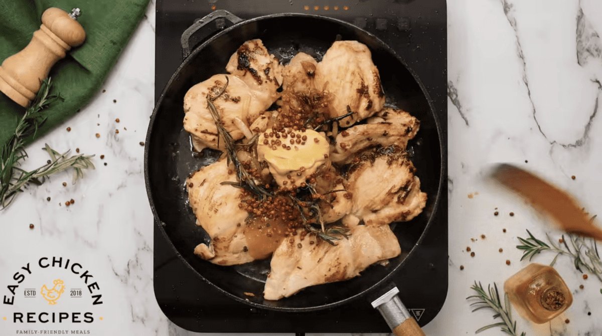 Mustard chicken in a pan with herbs and spices.