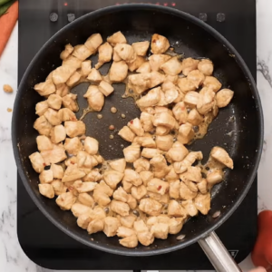 Chicken is cooking in a skillet.