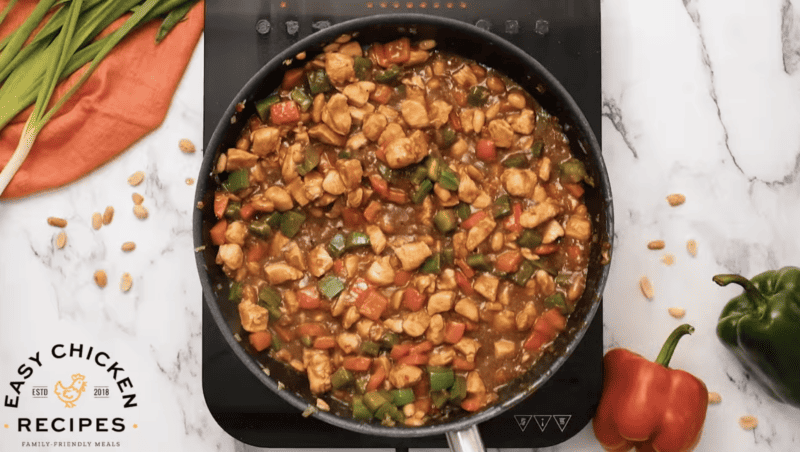 The sauce in the skillet has thickened with vegetables and chicken.