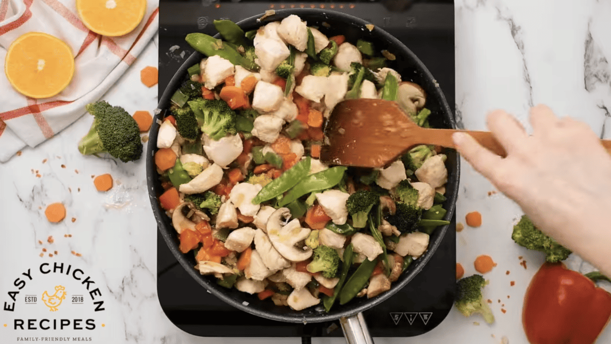 Chicken and vegetables are cooking together in a skillet. 