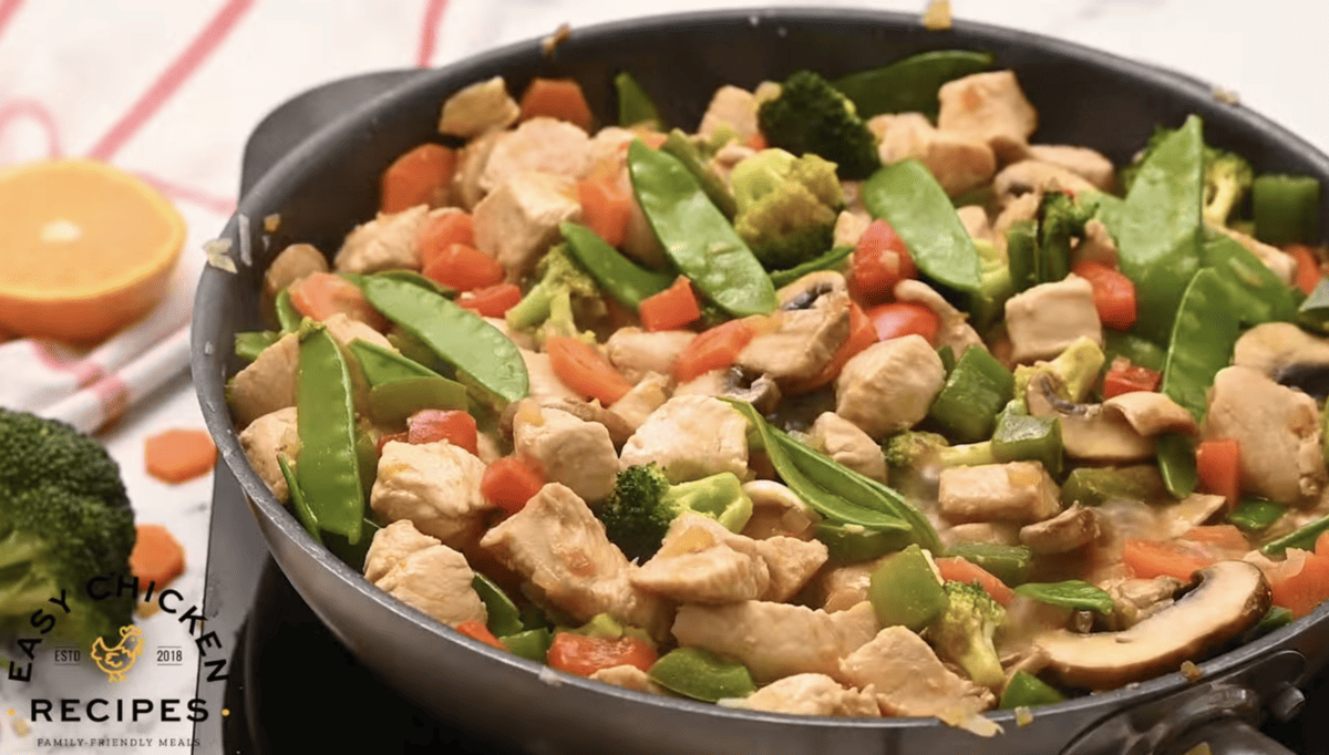 Chicken, vegetables and sauce are all combined in a skillet. 
