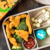 overhead shot of bento box made with dinosaur chicken nuggets and other dino food ideas
