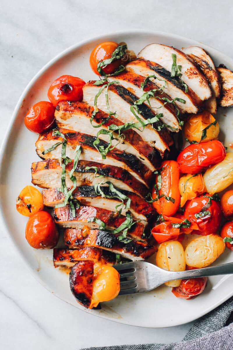 sliced balsamic chicken on plate with tomatoes