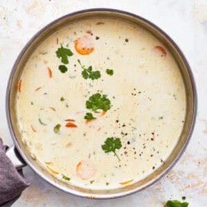 herb-topped creamy chicken soup in a pot.