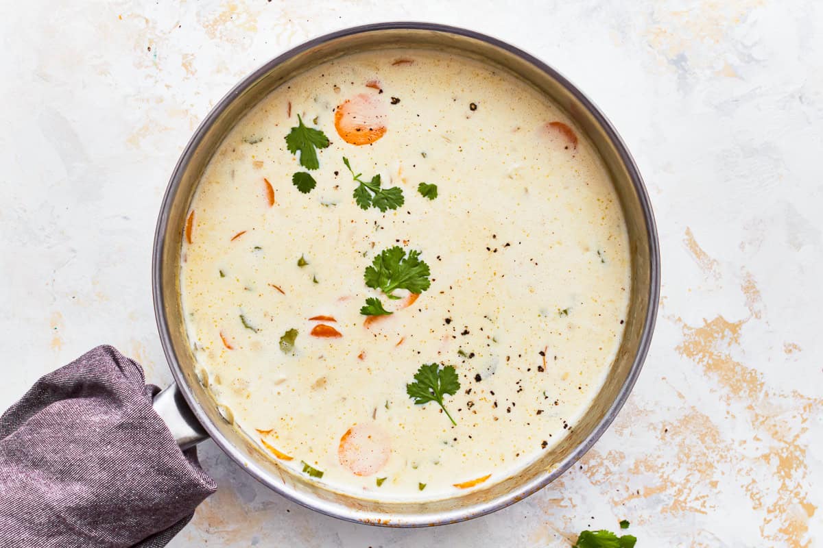 herb-topped creamy chicken soup in a pot.