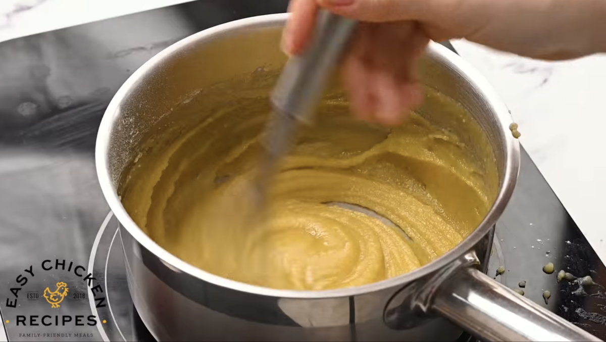 Oil, butter and flour are being whisked together in a small pot.
