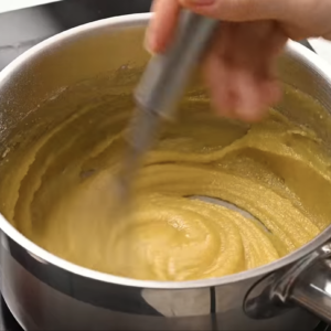 Oil, butter and flour are being whisked together in a small pot.
