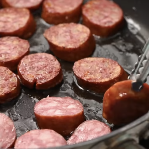 Andouille sausage is being cooked in a skillet.