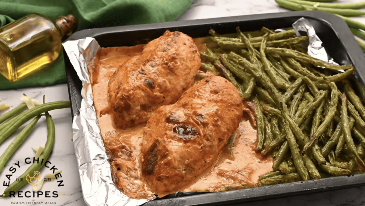Cooked chicken and green beans are on a sheet pan.