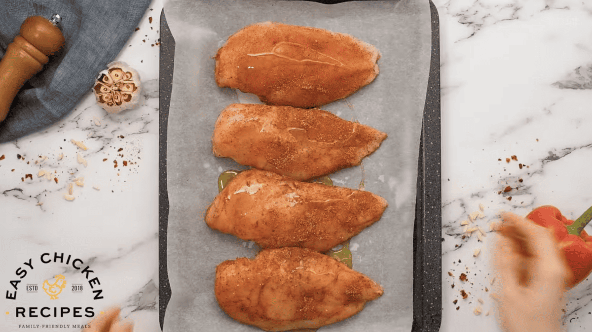 Romesco chicken breasts on a baking sheet.