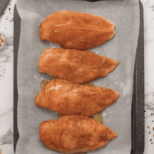 Romesco chicken breasts on a baking sheet.