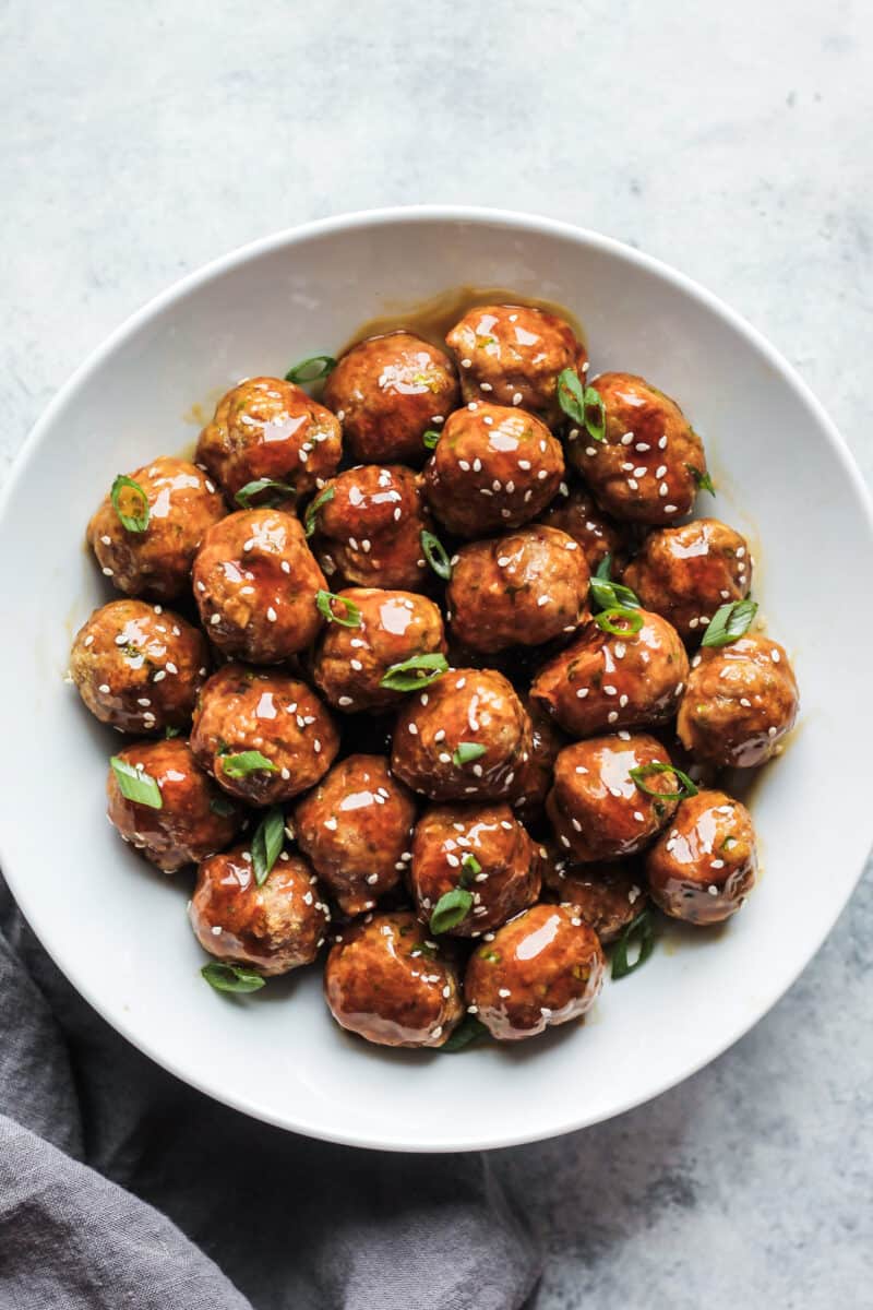 Asian chicken meatballs in a white bowl garnished with green onion