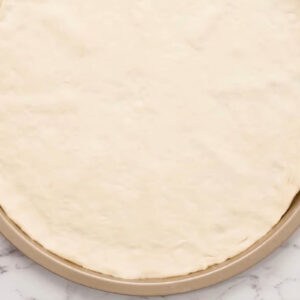 pizza dough stretched out in a pizza pan.
