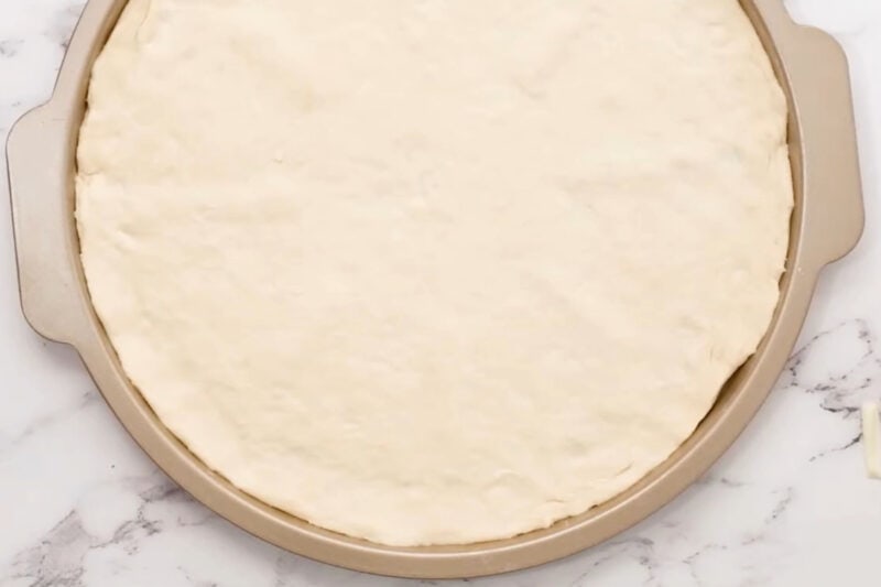 pizza dough stretched out in a pizza pan.