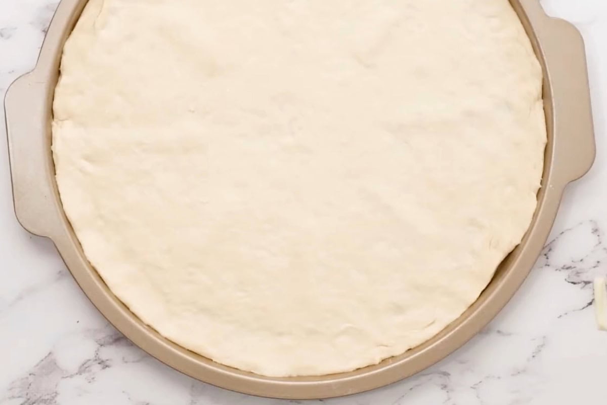 pizza dough stretched out in a pizza pan.