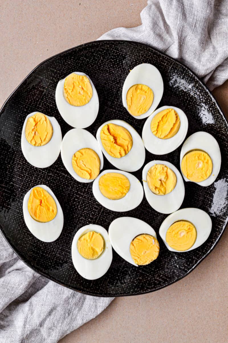 Instant Pot Hard Boiled Eggs cut in half on a black plate