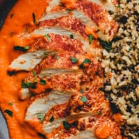 romesco chicken on a plate with sauce and rice