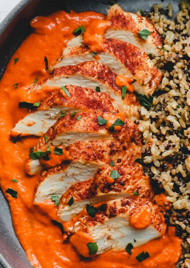 romesco chicken on a plate with sauce and rice