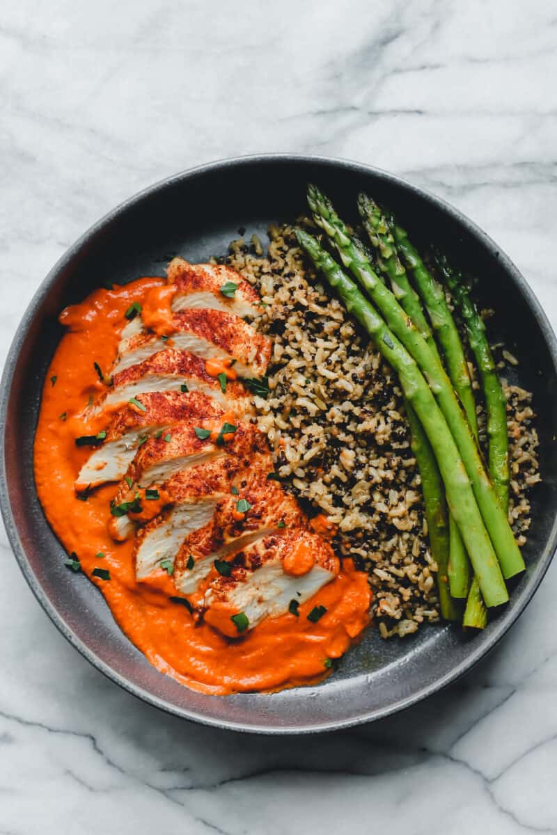 A plate with romesco chicken, asparagus, and rice.