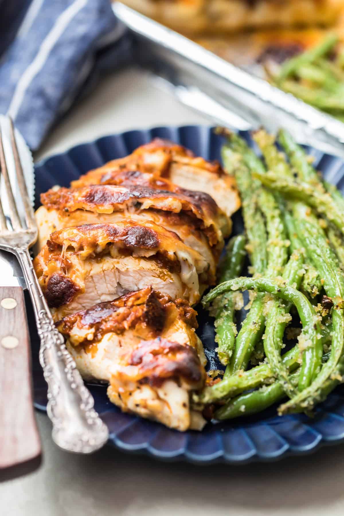 A plate with pesto chicken and green beans.