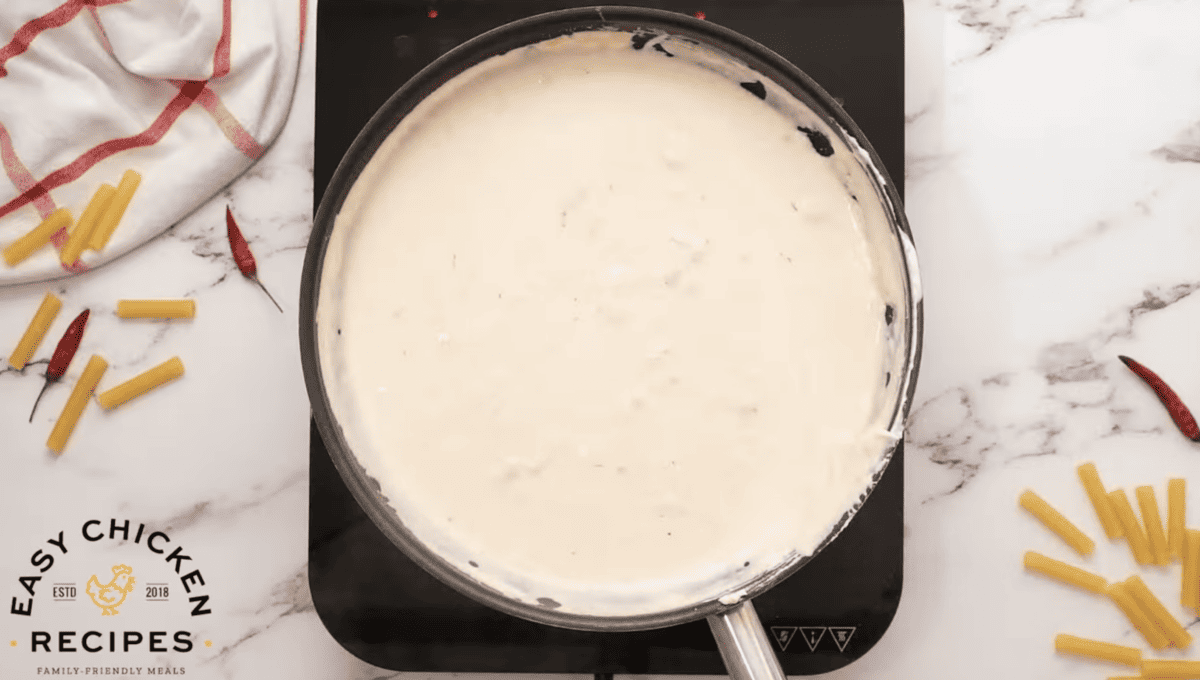 A creamy buffalo pasta sauce is bubbling in a skillet. 
