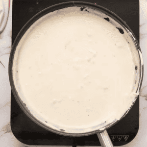 A creamy buffalo pasta sauce is bubbling in a skillet.