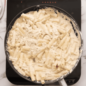 Pasta and chicken have been added to the skillet.