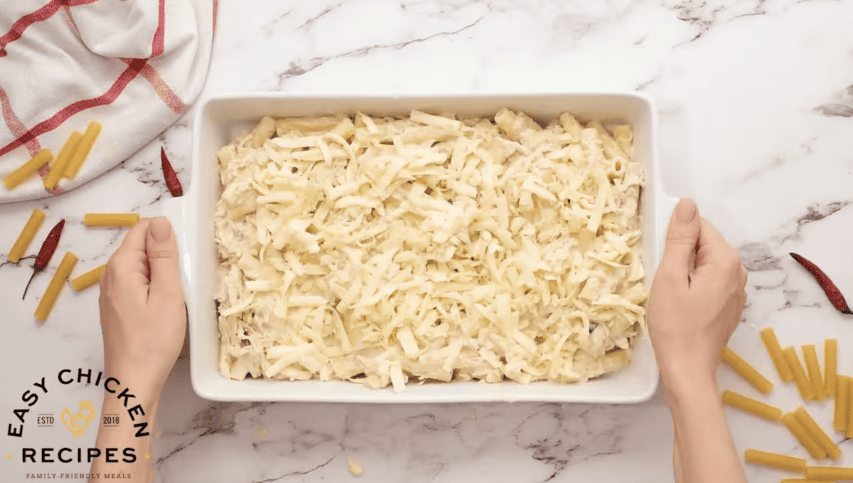 Mozzarella cheese is sprinkled across the top of ziti in a baking dish.
