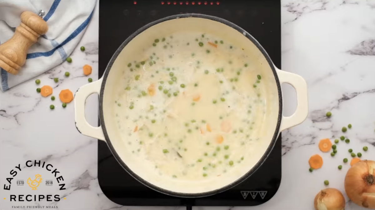 A dutch oven is filled with the milky mixture for chicken and dumplings. 