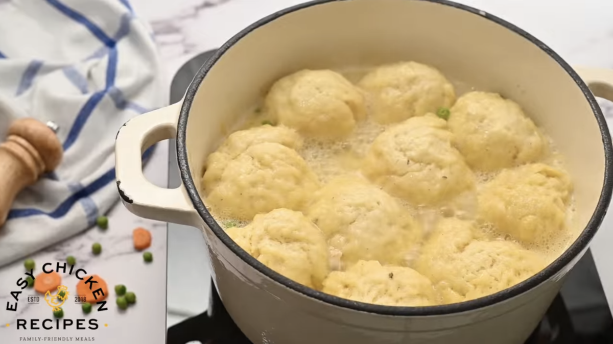 A pot is filled with cooked chicken and dumplings.