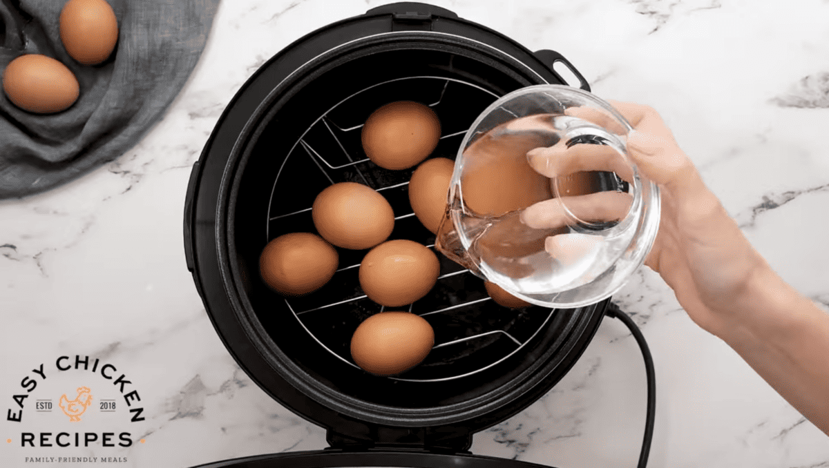 Water is being poured into the instant pot with eggs. 