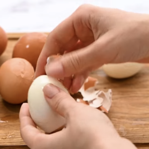 A hard boiled egg is being peeled.