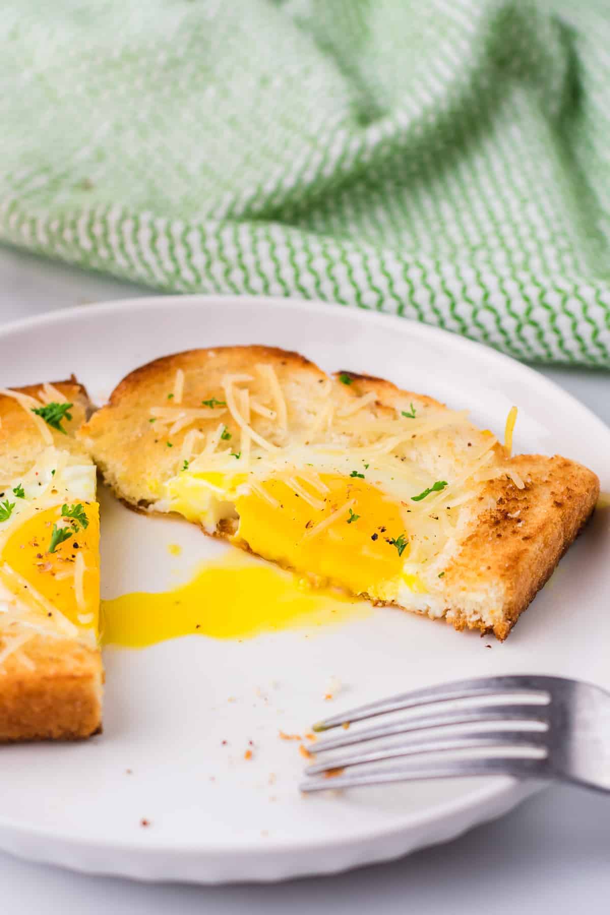 Toasted bread with an egg cooked inside, served with a fork.