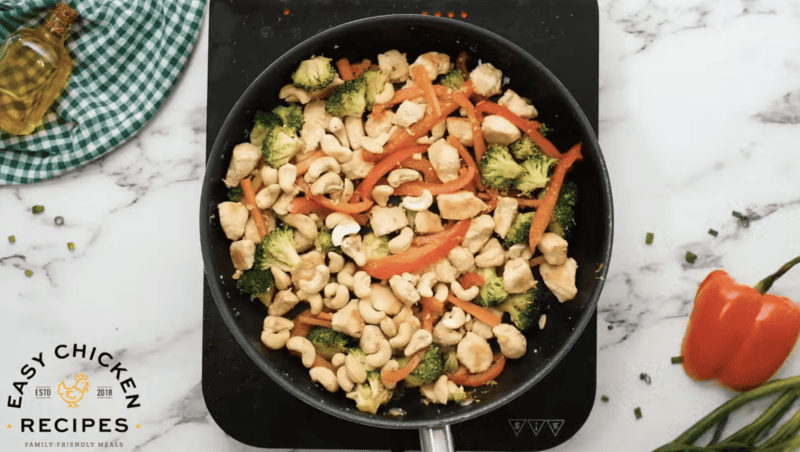 Chicken has been added to a pan filled with veggies.