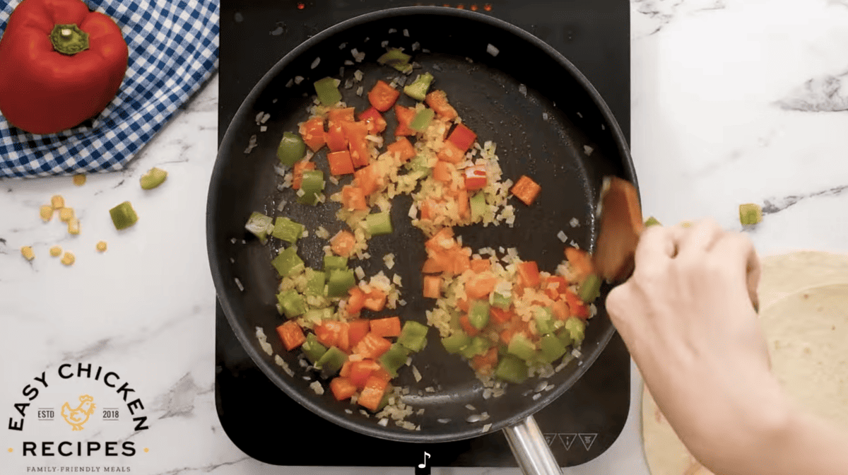 A person is preparing sauteed veggies in a frying pan.