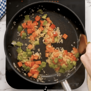 A person is preparing sauteed veggies in a frying pan.